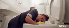 Woman scrubbing toilet with yellow glove