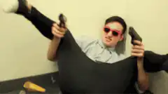 Man in red sunglasses holding two guns
