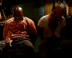 Two men gagged and bleeding in a dark room