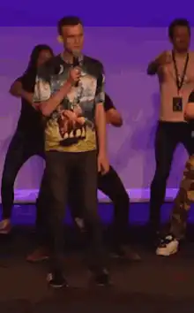 Man in tie-dye shirt singing on stage
