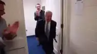 Man in suit walks into cheering locker room