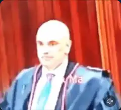 Bald man in blue robe speaking