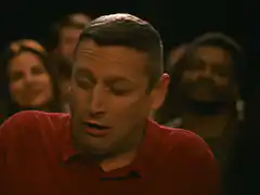Man in red shirt singing with eyes closed