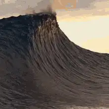 Massive ocean wave crashing at sunset