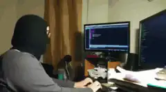 Hacker typing and looking at camera