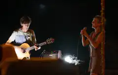 man playing guitar and woman singing on stage