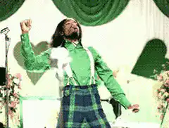 Singer in green shirt and plaid pants dancing