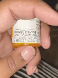 Hand holding promethazine pill bottle