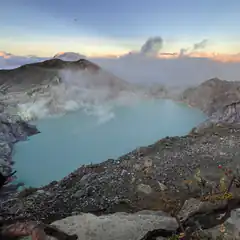 Turquoise crater lake with steam rising