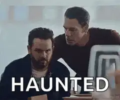 Two men looking at a screen with the word HAUNTED