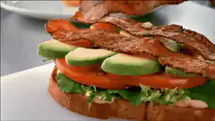 Bacon being added to a sandwich