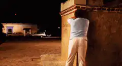 woman peeing on wall at night