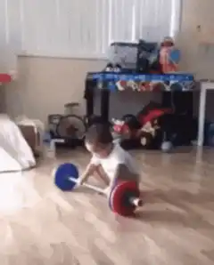 Toddler lifts toy barbell and celebrates