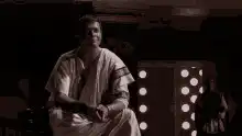 Man in robe stands up from chair