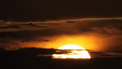 Sun rising behind clouds