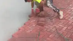 Worker laying red brick pavers
