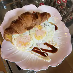 croissant and fried eggs on pink plate