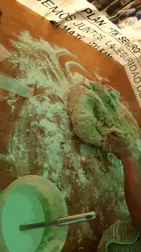 Hands kneading dough with green powder