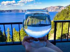 hand holding wine glass with lake view