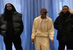 Three men dancing in front of blue curtain