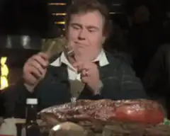 Man eating large ham with beer
