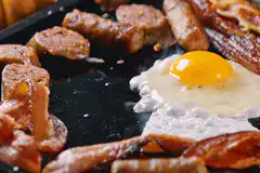 Frying egg and sausage on griddle