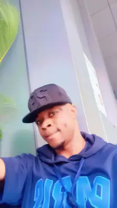 Man in blue hoodie and cap smiling