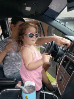 little girl driving car with sunglasses