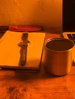 watch on notebook next to coffee mug