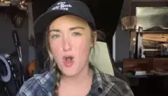 Girl in hat makes faces and falls over