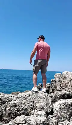 man standing on rocky cliff overlooking ocean