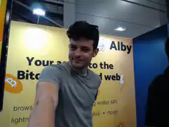 Man posing in front of Alby Bitcoin banner