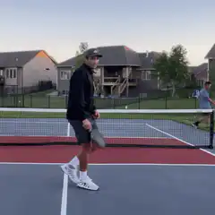 Man points at camera on pickleball court