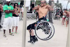 Shirtless man in wheelchair doing a handstand