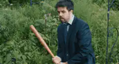 Man in suit swinging baseball bat