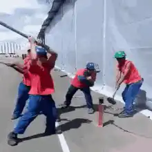 Construction workers smashing a pipe with sledgehammers