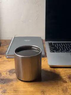 metal cup on desk next to laptop