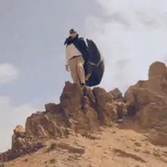 Man with briefcase and cape on rocky hill