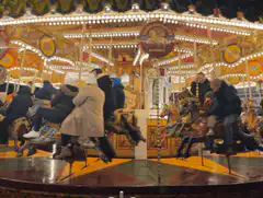 People riding a lit-up carousel at night