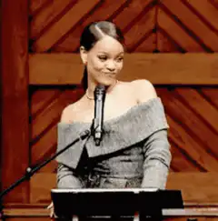 Rihanna playing with her hair at a podium