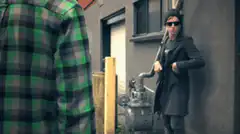 Man in coat and sunglasses holding a pipe