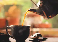 Pouring tea from a kettle into a cup