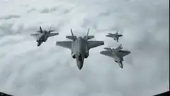 F-22 Raptors flying in formation above clouds