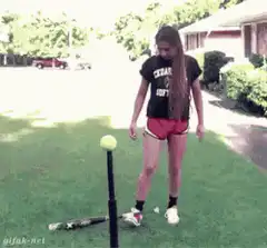Girl hits tee ball with bat