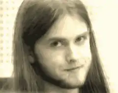 Long-haired man smirking and closing eyes