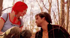 Redhead girl and boy kiss in the woods
