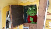 Frog mascot waves from window
