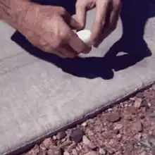 Hands cracking an egg on hot concrete