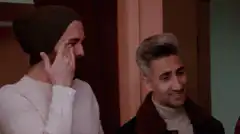 Man wiping tear while friend smiles