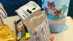 Hand holding a plastic juice box with Japanese text